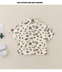 Detail of short-sleeved cotton shirt for boys with brown pebble print on beige fabric