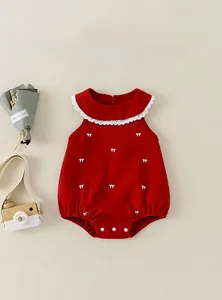 Détail d'une barboteuse rouge pour bébé avec col en dentelle et motifs nœuds