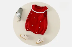 Détail d'un body bébé rouge avec col en dentelle blanche et motifs nœuds