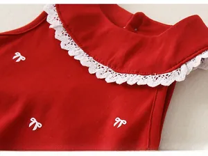 Détail du haut rouge pour bébé fille avec col en dentelle blanche et petits nœuds 3D