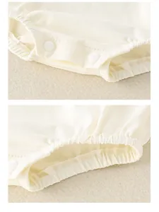 Detail of baby bodysuit featuring soft resin snap buttons and elastic leg openings