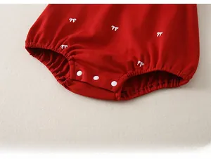 Détail de l'entrejambe d'un barboteuse rouge avec boutons pressions et broderie