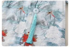 Detail of baby romper featuring lotus prints, jade-like ring and tassel accessory