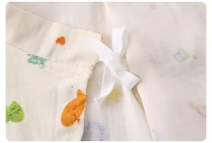 Close-up of baby romper showing breathable cotton gauze texture and ribbon ties