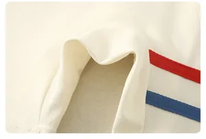Close-up of off-white piqué cotton fabric showing texture and red-blue striped edges