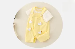 Détail d'un ensemble d'été pour bébé avec canards en 3D sur une salopette jaune