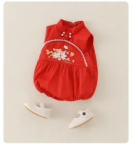 Detail of red newborn romper with floral embroidery and white Mary Jane shoes