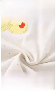 Close-up of soft cotton knit fabric with colorful specks and cartoon deer embroidery