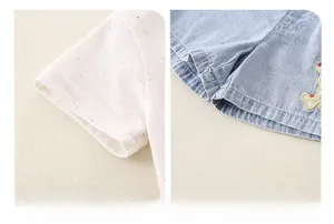 Detail of soft cotton sleeve with colorful polka dots and denim shorts with bear embroidery
