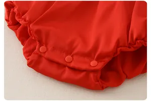 Detail of snap button crotch on red newborn romper for easy diaper changes