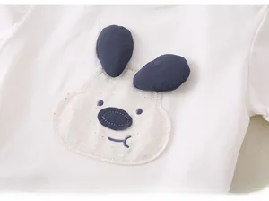Détail du t-shirt blanc en coton avec oreilles de chien 3D et broderie en applique