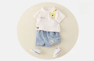Flat lay of cotton infant summer set with cartoon giraffe tee and denim shorts
