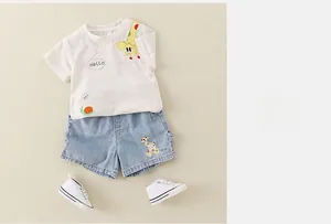 Flat lay of cotton infant summer set featuring cartoon giraffe print and denim shorts