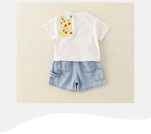Flat lay of baby summer set with cream giraffe t-shirt and light blue denim shorts