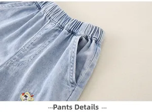 Close-up of light blue denim pants featuring elastic waistband and colorful cartoon embroidery