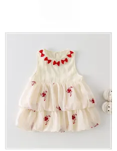 Détails de la robe bébé ivoire avec nœuds rouges et broderie florale sur tulle souple