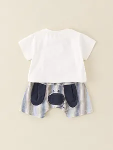 Ensemble d'été bébé avec t-shirt blanc et short rayé motif chiot sur fond beige clair