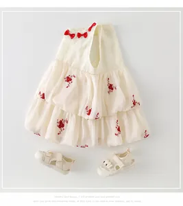 Détail d'une robe en coton pour bébé avec broderies florales rouges et sandales assorties