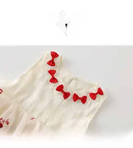 Détails du col d'une robe en coton pour bébé avec nœuds rouges et dentelle brodée