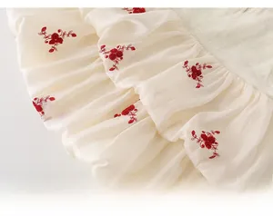 Gros plan détaillé des broderies florales rouges sur la robe d'été plissée en coton