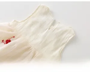 Détail d'une robe en coton pour bébé fille avec broderies et bouton au dos