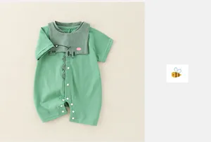 Detail of baby summer romper featuring a cute green dinosaur cartoon appliqué and snap buttons
