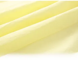 Close-up of lightweight pale yellow cotton fabric showing soft texture and fine weave