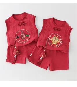Detail of traditional red cotton baby vest and shorts with embroidery and tassel charms