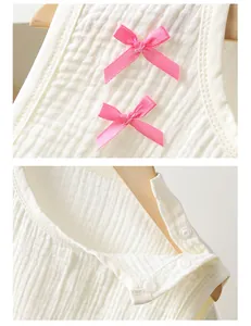 Detail van witte katoenen gaasstof met roze strikjes en drukknopen op houten hanger