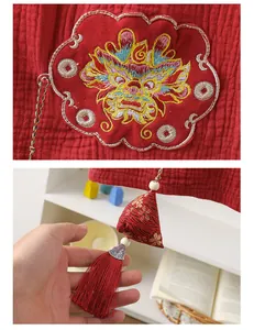 Detail of traditional Chinese dragon embroidery and red tassel on cotton baby suit