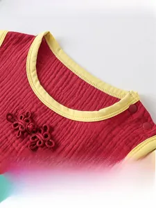 Détail d'un barboteuse rouge pour bébé avec bouton chinois et coton à texture douce