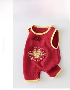 Détail de barboteuse bébé en gaze de coton rouge avec broderie dragon et nœuds