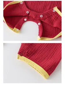Détails d'une barboteuse bébé rouge en coton avec boutons-pression et bordure jaune