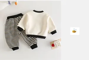 Flat lay of baby cotton set with beige long-sleeve top and black striped pants
