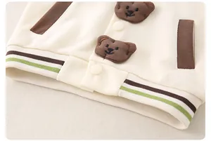 Dettaglio del cardigan in maglia per neonati con toppe a forma di orso e bordo a righe