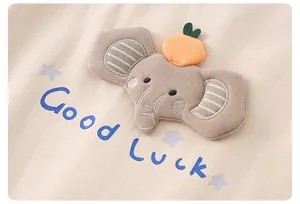 Detail eines Baby-Baumwolloberteils mit Elefanten-Patch und blauem Good Luck Aufdruck