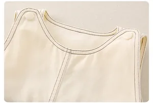 Dettaglio salopette neonato in cotone con cuciture a contrasto e bottone sulla spalla