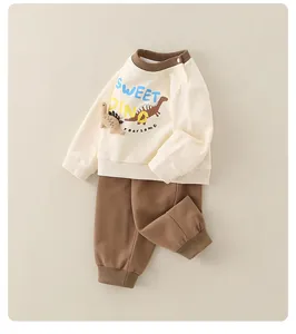 Details eines Baumwoll-Babysets mit Dinosaurier-Sweatshirt und brauner Hose