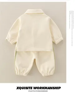 Detail of baby tracksuit showing elastic cuffs, polo collar, and beige cotton fabric