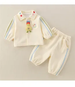 Detail of baby cream tracksuit featuring colorful caterpillar doll and festive embroidery