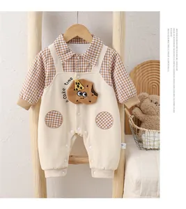 Detail of baby cotton romper with cookie embroidery and plaid trim on a wooden ladder