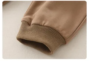 Detailaufnahme der braunen Baumwoll-Rippbündchen an Kapuzenpullover und Hose für Babys
