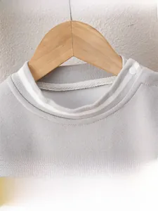 Detailed macro view of soft gray knitted infant top with ribbed collar and shoulder button