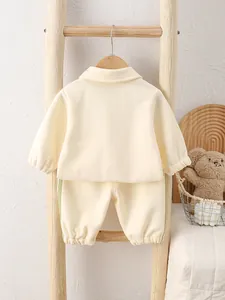 Two-piece beige baby outfit featuring long sleeve polo top and pants with green side stripes