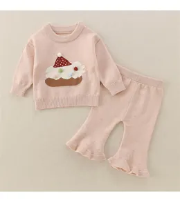 Detail eines rosa gestrickten Kleinkind-Outfits mit Rüschensaum und strukturiertem Motiv