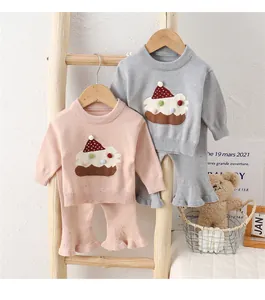 Detail von Baby-Stricksets mit Cupcake-Stickerei und Rüschenhosen an einer Kleiderstange