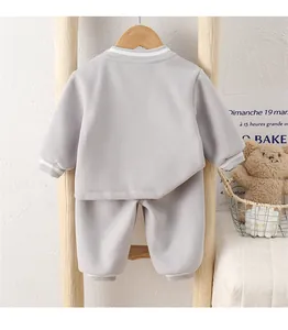Detail of baby cotton sweater set with ribbed striped cuffs on a wooden hanger