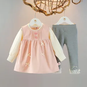 Detail of baby girl cotton set with pink dress, beige bows and lace ruffled leggings