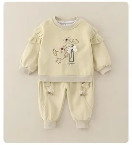 Detail of beige cotton set for toddler girls with floral embroidery and ruffle shoulders