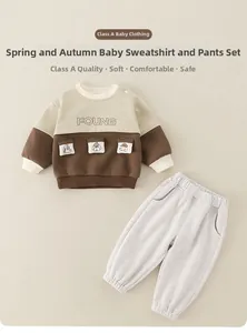 Detail of baby boy cotton tracksuit featuring cream patchwork sweatshirt and grey joggers